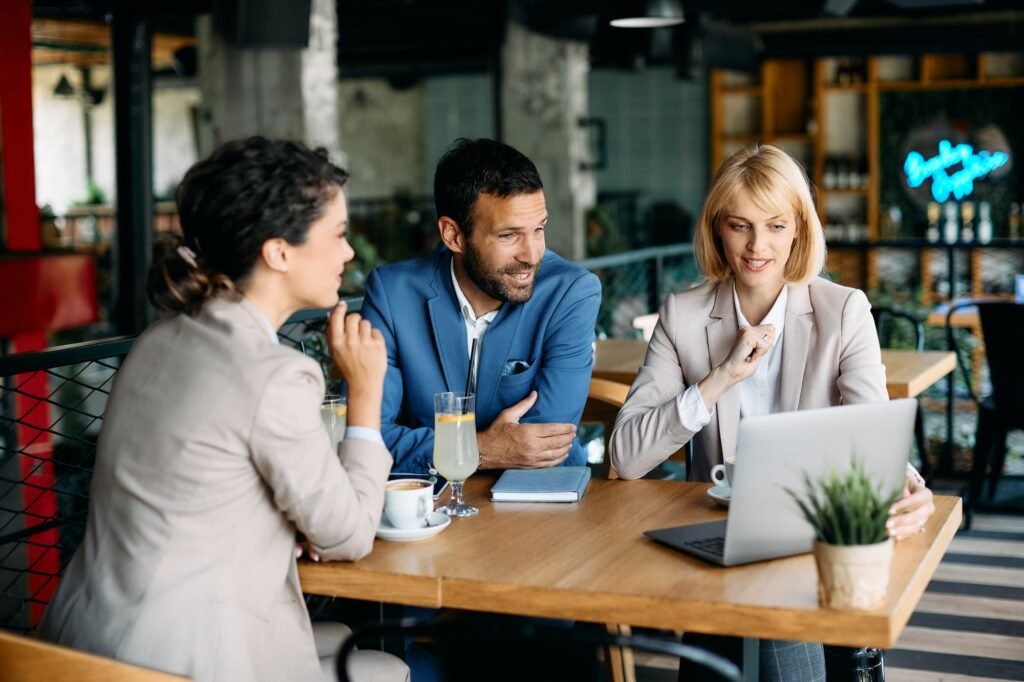 group of colleagues using laptop during business meeting in a cafe